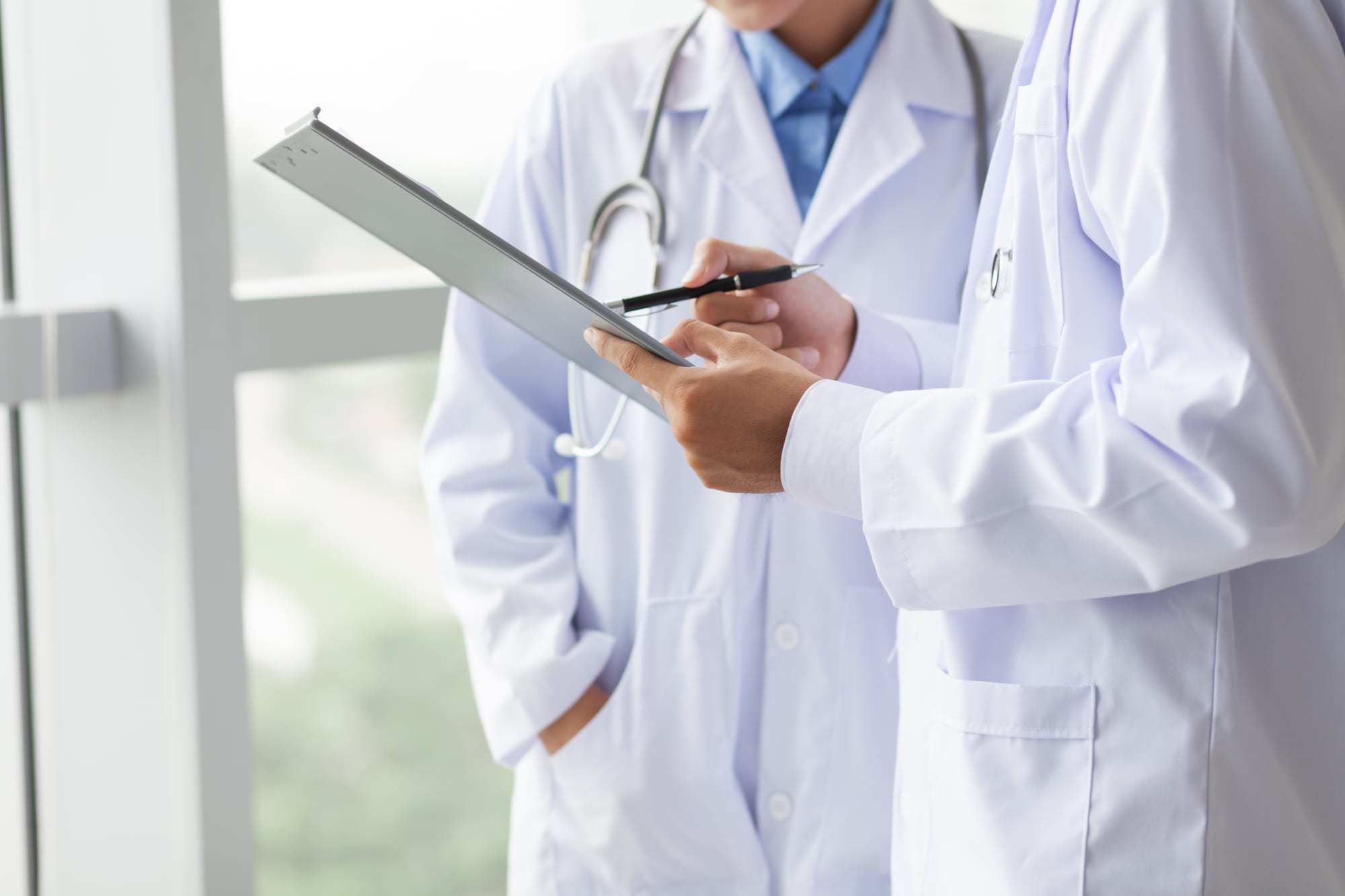 Close-up-of-torsos-of-two-doctors-sharing-notes